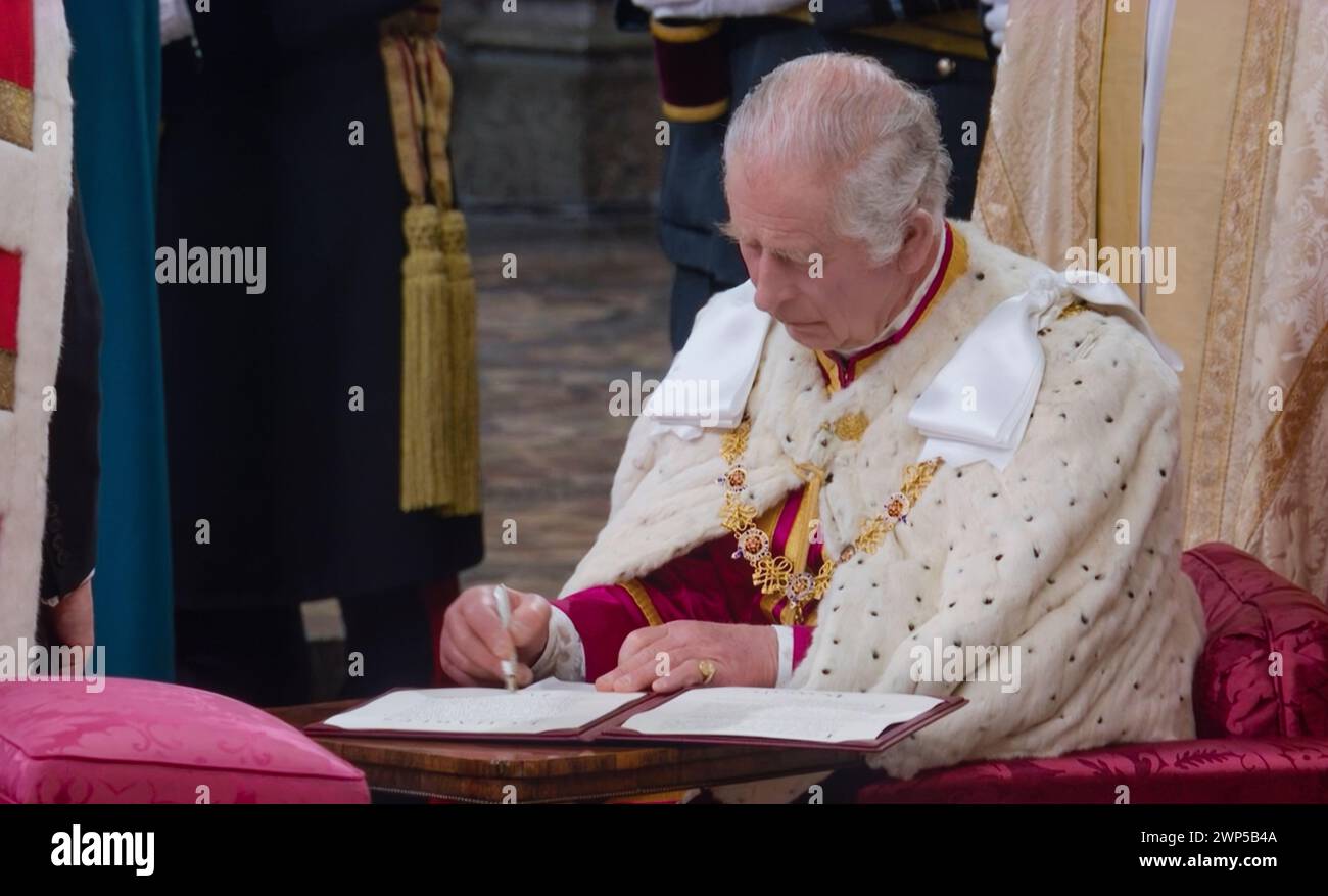 King Charles III signing Coronation oath, pledging to serve the people and rule according to law. The Coronation ceremony interior at Westminster Abbey Westminster London UK May 6th 2023 Stock Photo