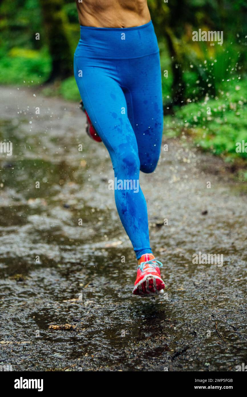 Female athlete running through puddle Stock Photo