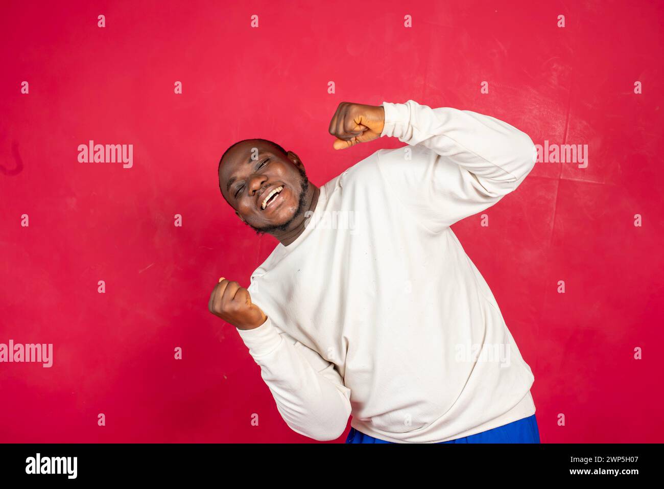 Extremely happy excited young african american man win lottery bet standing pleased jumping joyfully triumphing clench fists celebrating success look Stock Photo