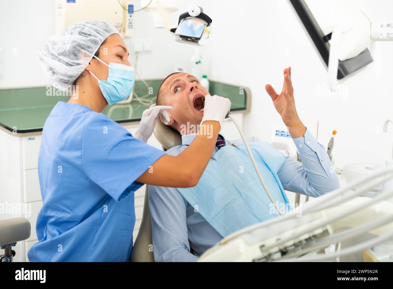 Tooth And Computer Dentist checks the patient teeth using special device and computer ...