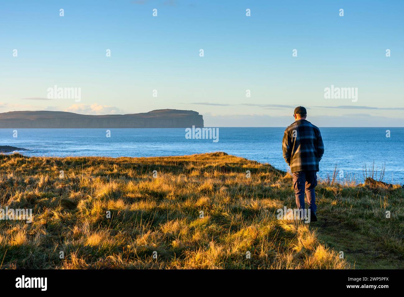 A walker on the coastal path near Scarfskerry looking towards Dunnet Head in the distance.  Near Thurso, Caithness, Scotland, UK. Stock Photo