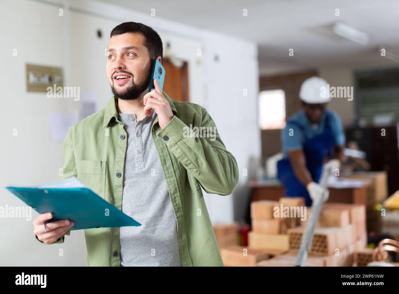 Construction manager with paper folder having telephone conversation Stock Photo