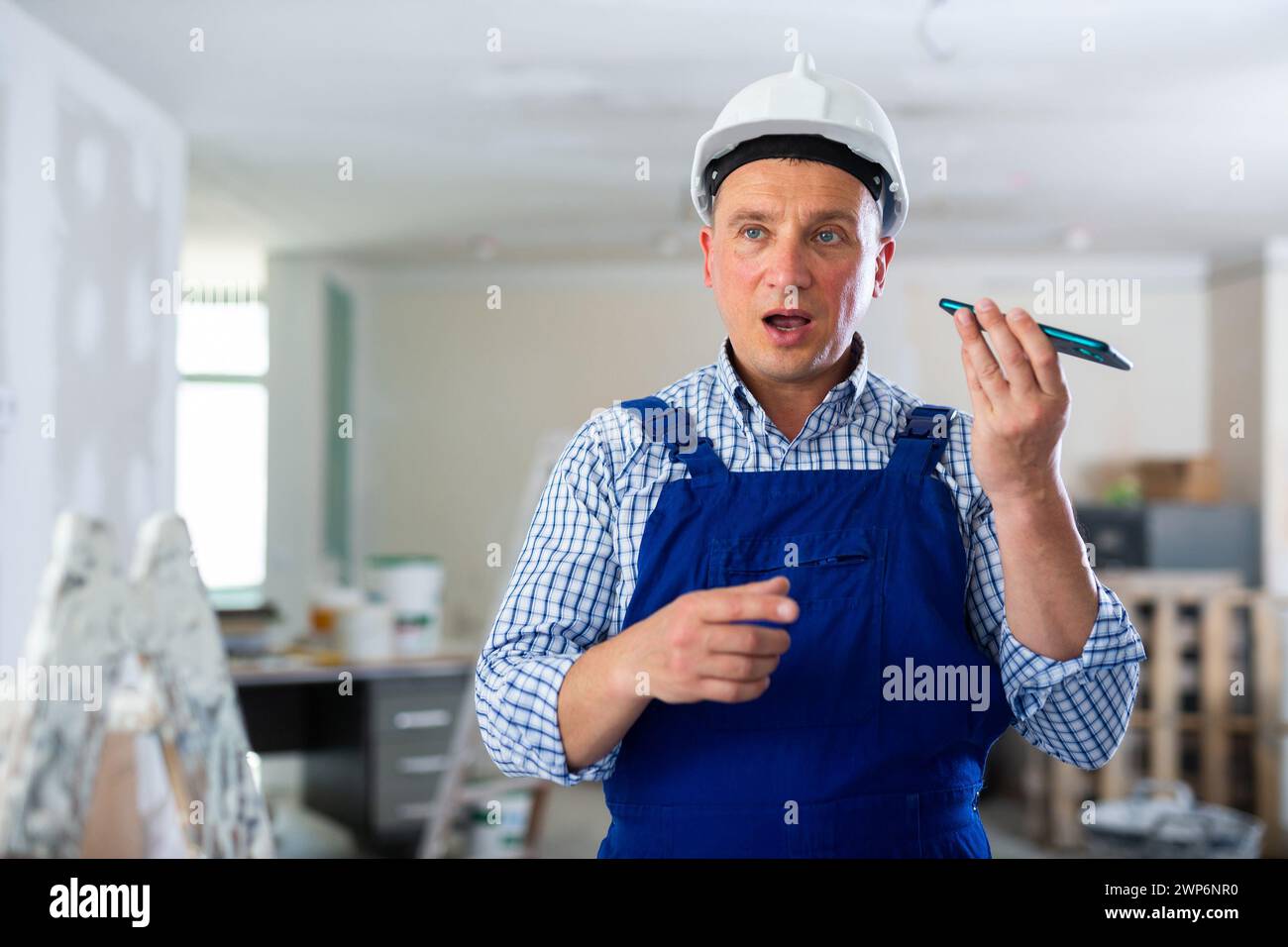 Foreman using smartphone, recording voice message Stock Photo