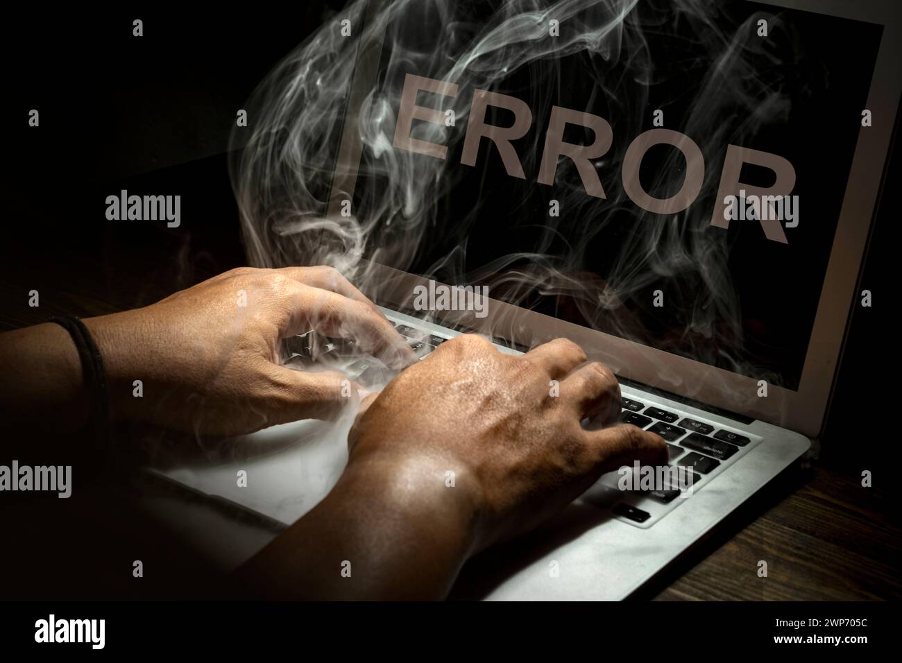 Close up hand typing a laptop burned with smokes on a wooden desk ...