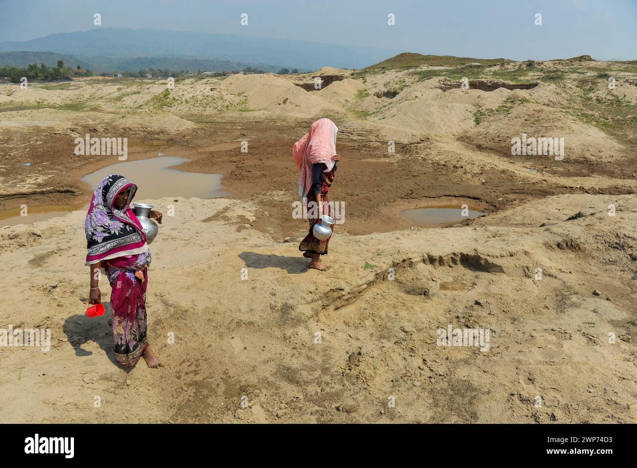 Non Exclusive: Two housewives are collecting water for household use from an almost dry reservoir in Kalairag area of Bholaganj bordering Companiganj Stock Photo
