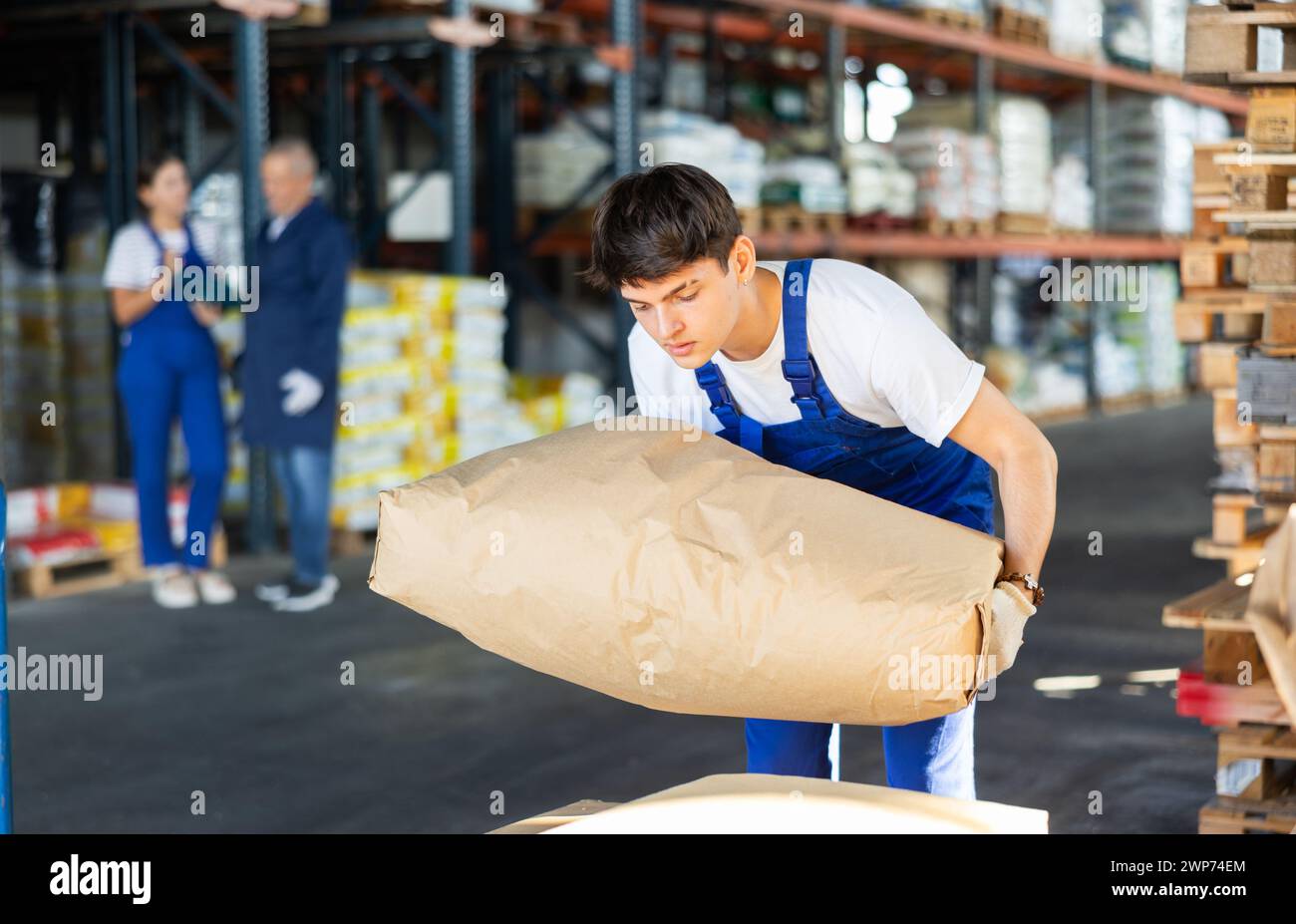 Young guy loading bags on cart in warehouse Stock Photo