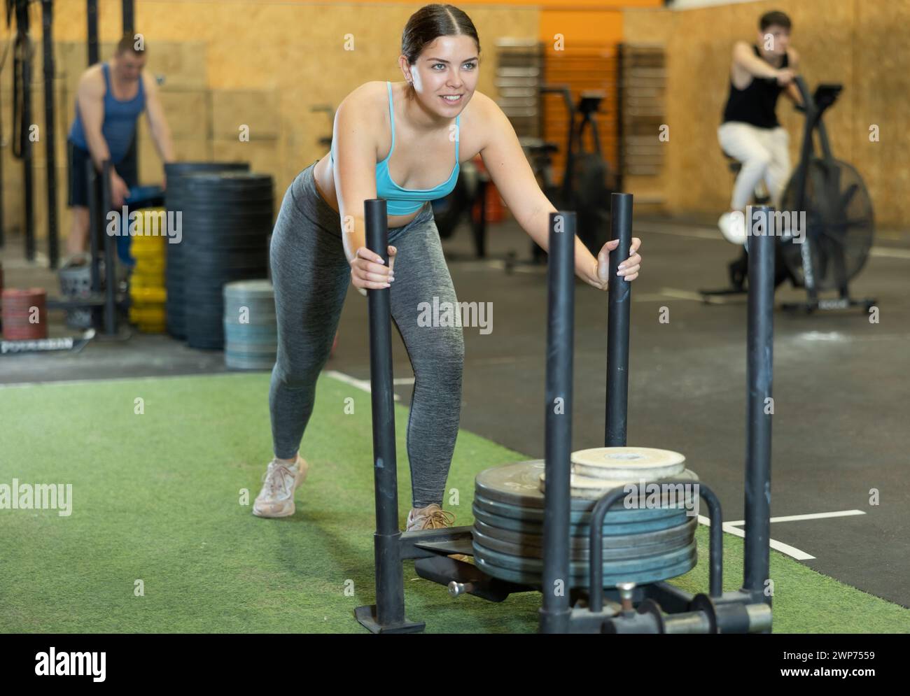Motivated young woman performing heavy sled push in gym Stock Photo Alamy