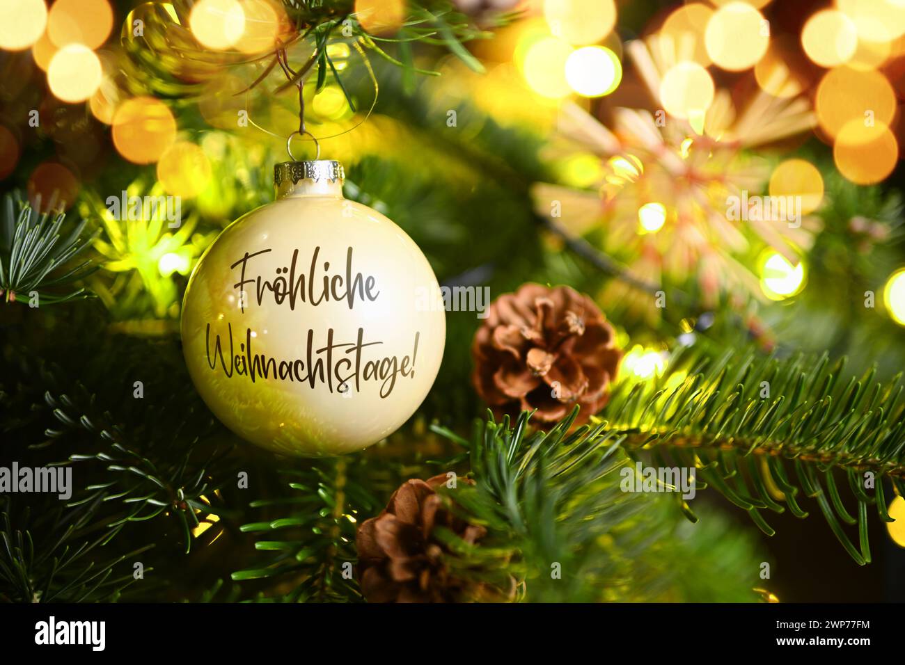 FOTOMONTAGE, Weihnachtskugel mit Aufschrift Fröhliche Weihnachtstage hängt an einem Weihnachtsbaum Stock Photo