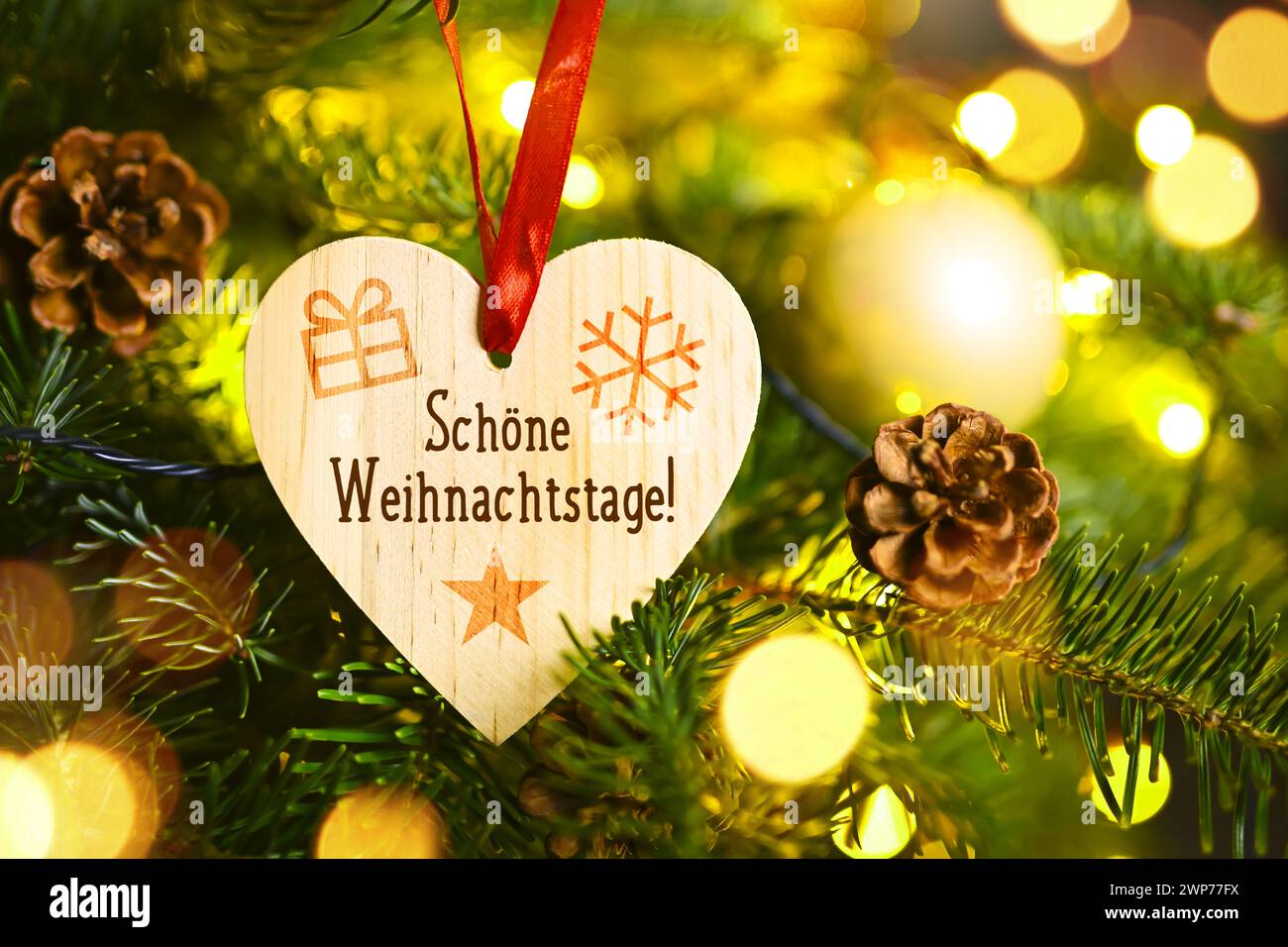 FOTOMONTAGE, Hölzernes Herz mit Aufschrift Schöne Weihnachtstage hängt an einem Weihnachtsbaum Stock Photo