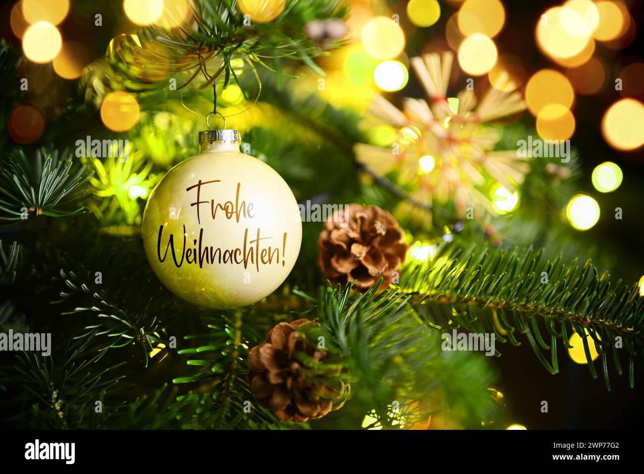 FOTOMONTAGE, Weihnachtskugel mit Aufschrift Frohe Weihnachten hängt an einem Weihnachtsbaum Stock Photo