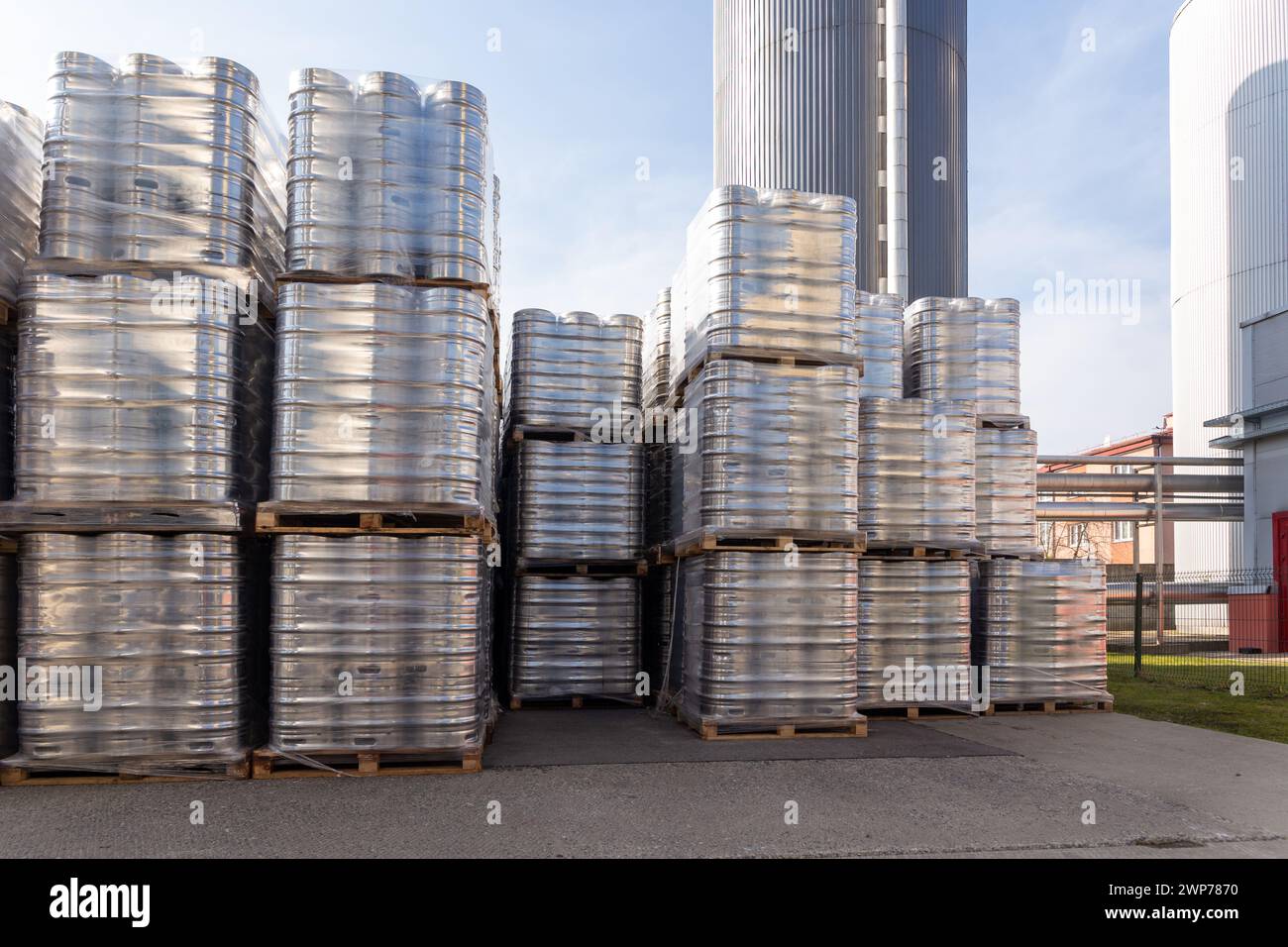 Large amount of aluminium beer kegs stacked on each other with euro palettes and wrapped around with vinyl foil. The beer ready for shipment is bottle Stock Photo