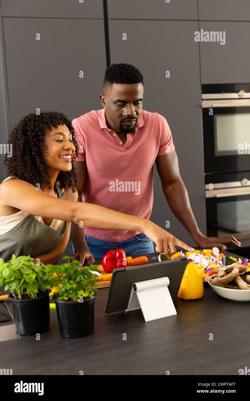 Young biracial African American couple are cooking together in a modern ...