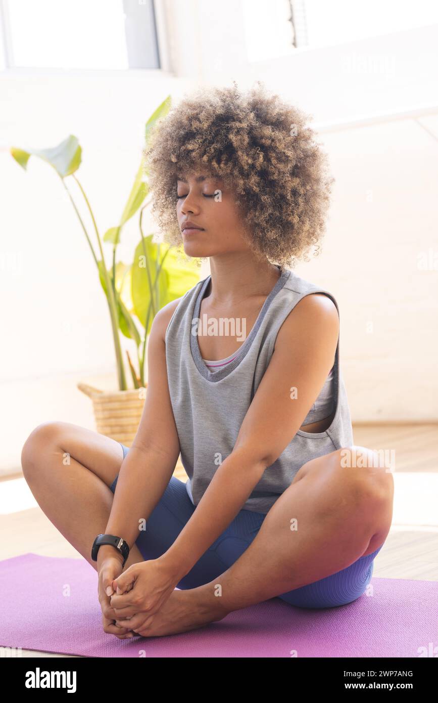 Young biracial woman practices yoga in a bright studio setting Stock Photo