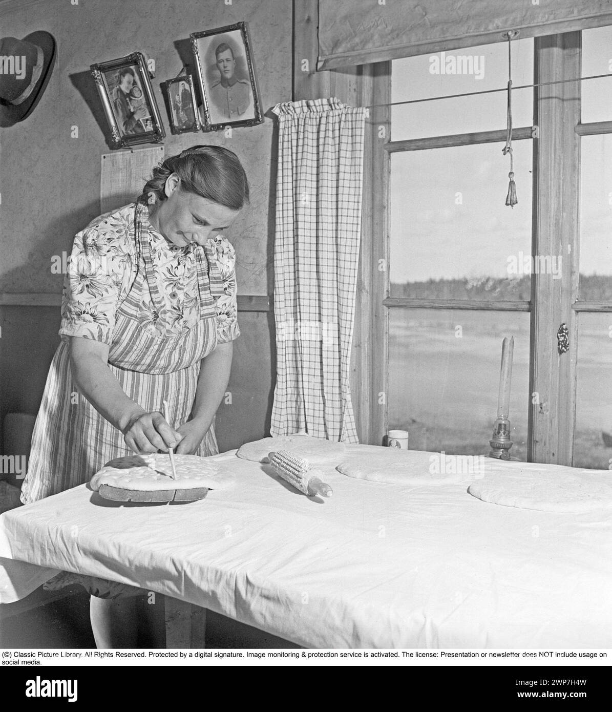 Baking bread 1949. Interior of a kitchen with a woman baking bread. She prepares the dough before putting it into the oven. A rural kitchen in Lapland Sweden 1949. Kristoffersson ref AS83-4 Stock Photo