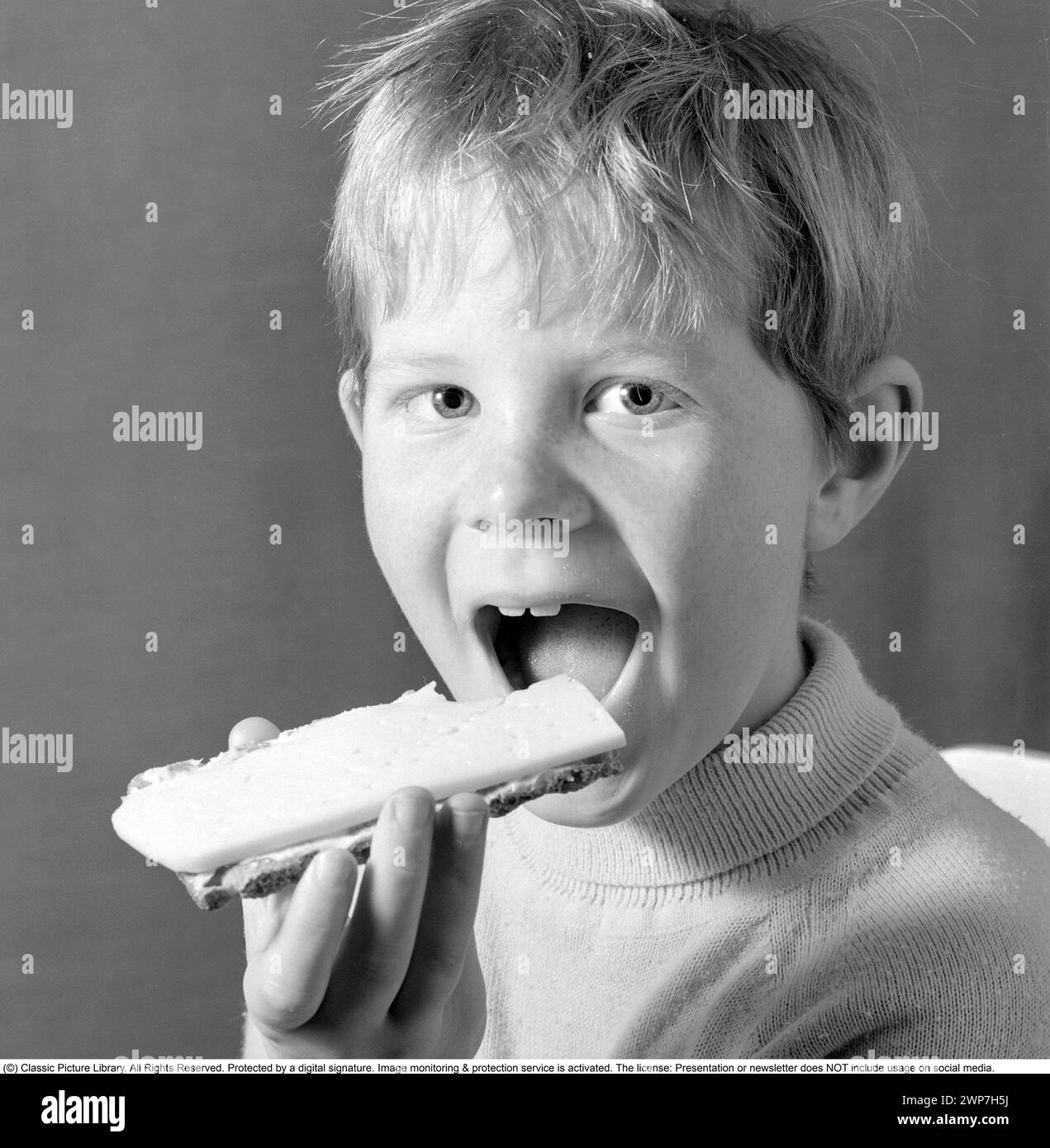 In the 1960s. A boy is eating a cheese sandwich. 1969. Conard ref 5818 Stock Photo