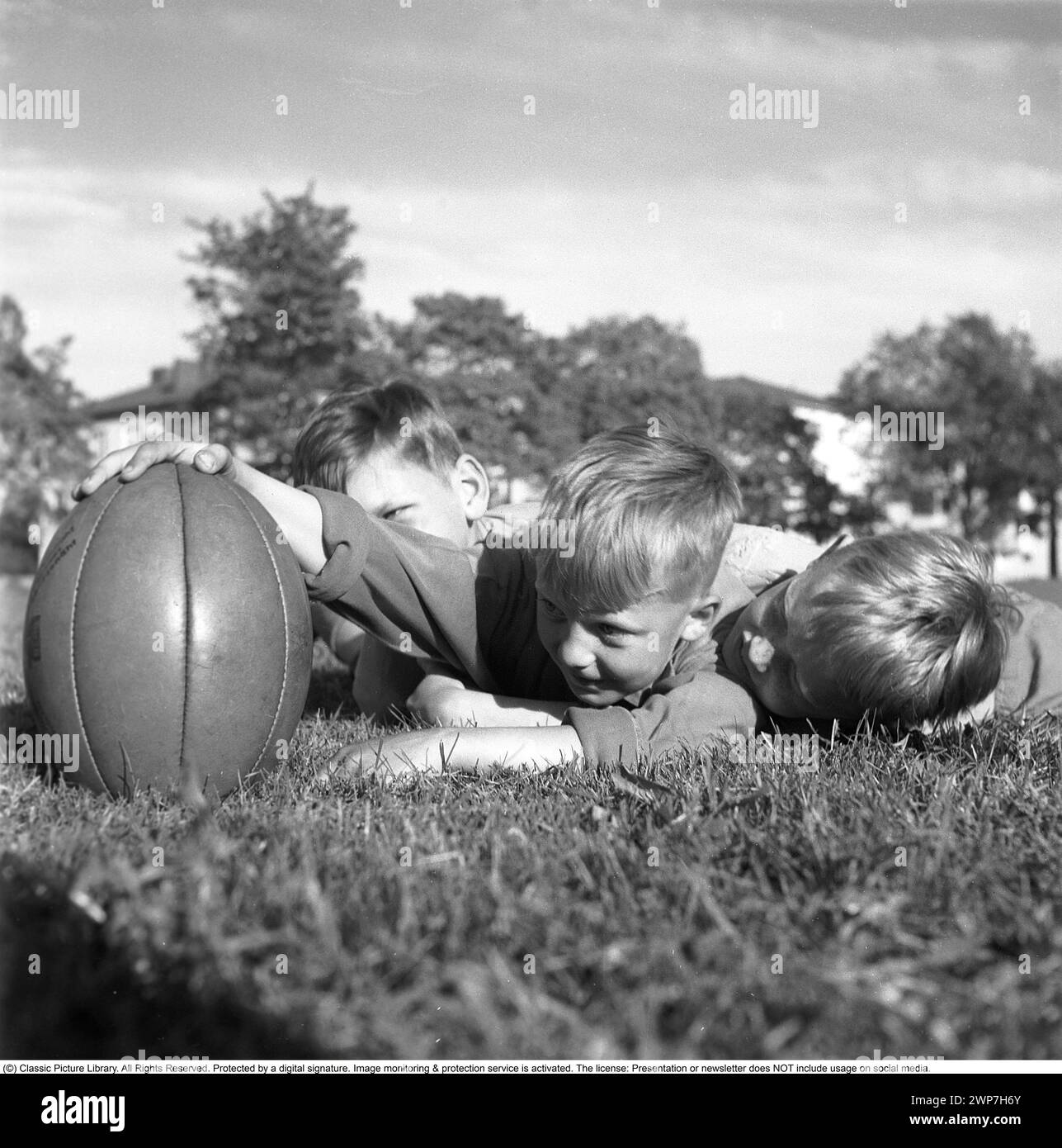 Rugby 1940. Three young rugby players lying in the grass on the rugby field, one holding the rugby ball. The rugby ball has an oval shape, four panels and a weight of about 400 grams. 1942. Kristoffersson ref A56-5 Stock Photo