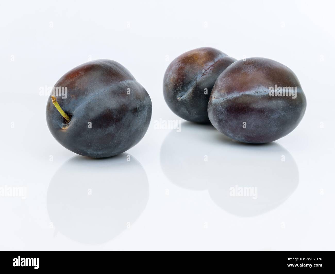 Three plums isolated on white background close up with reflection Stock Photo