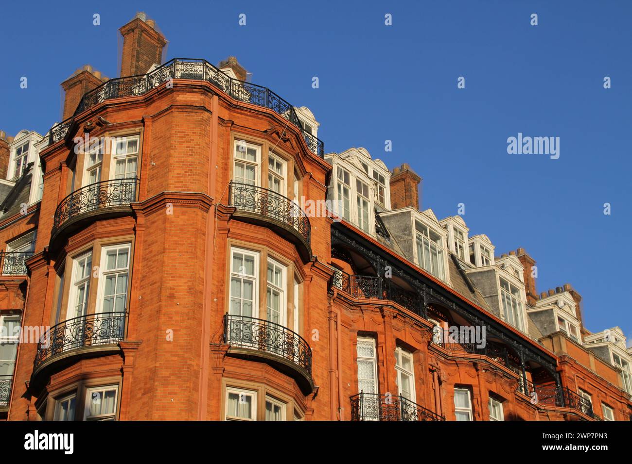 A tall red building with numerous windows and balconies in London Stock Photo
