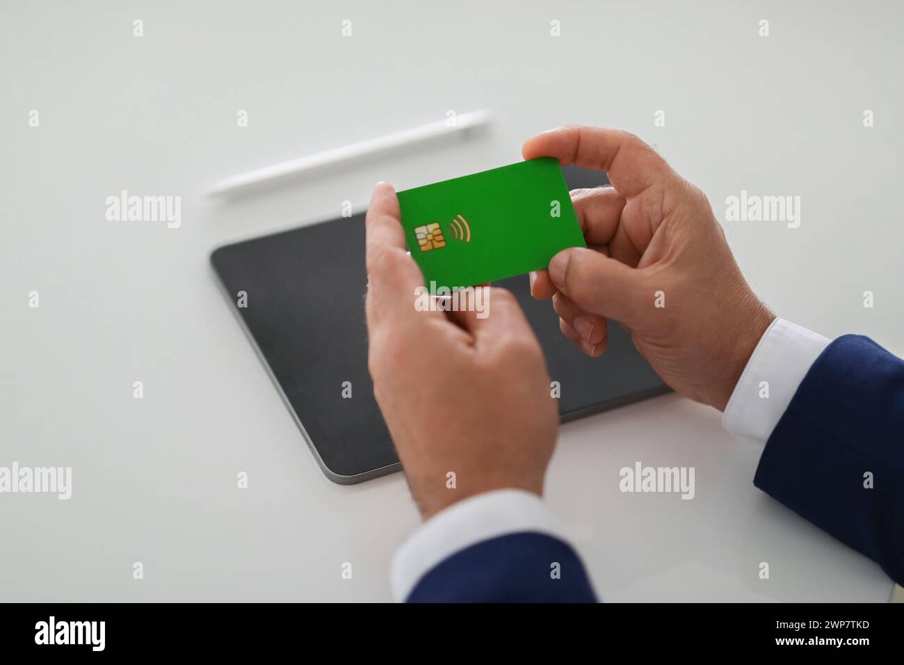Close-up of a businessman's hands carefully examining a green bank card Stock Photo