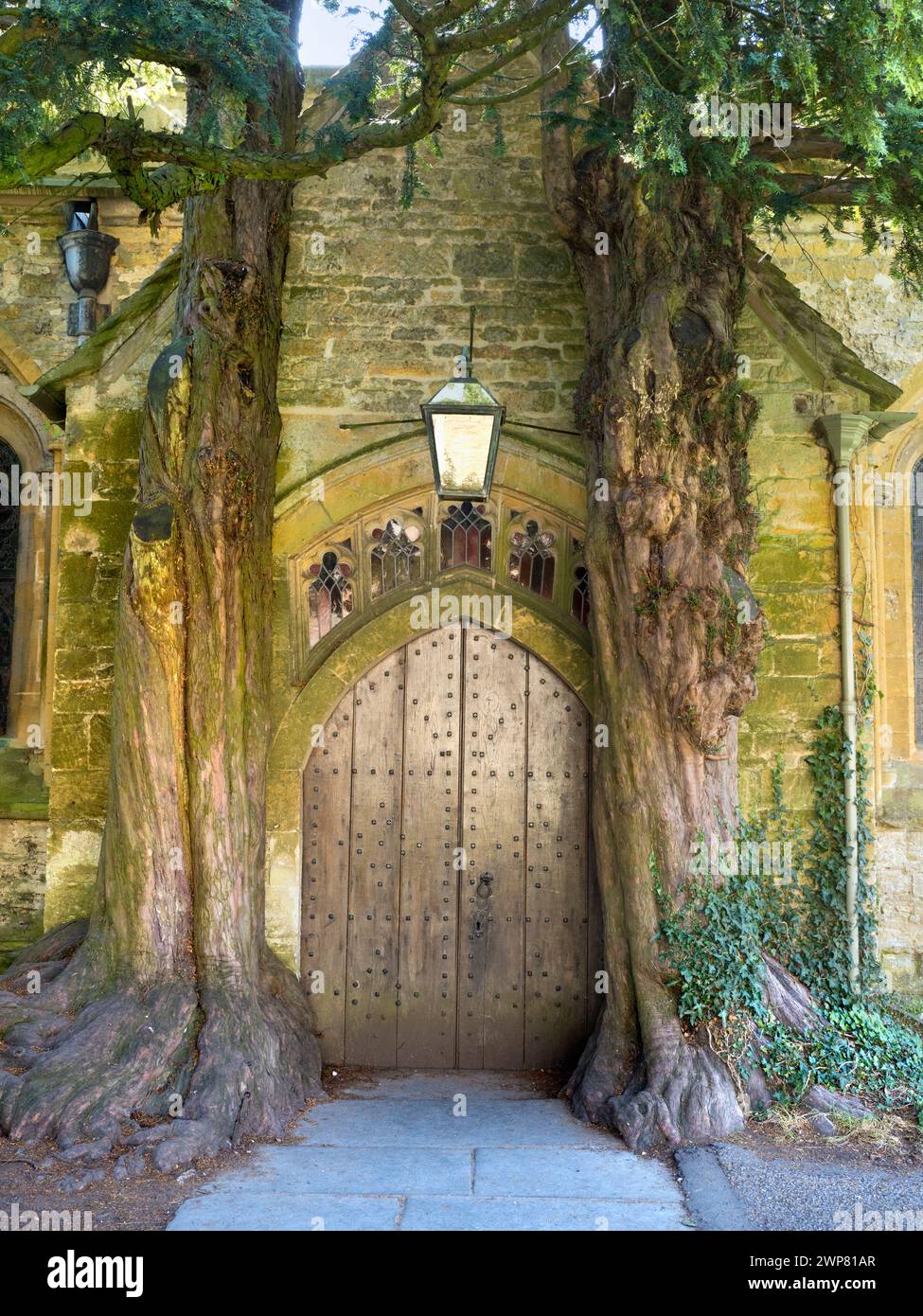 Hidden away in the grounds of the historic St EdwardÕs Church Stow-on-the-Wold in the Cotswolds can be seen this magical medieval church door flanked Stock Photo