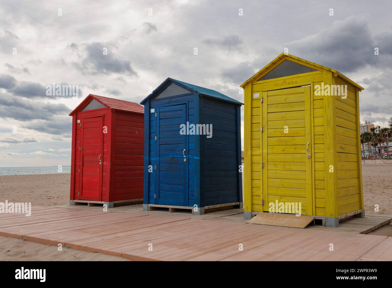 Colorful wooden huts on Villajoyosa beach backlit on cloudy day, Spain Stock Photo