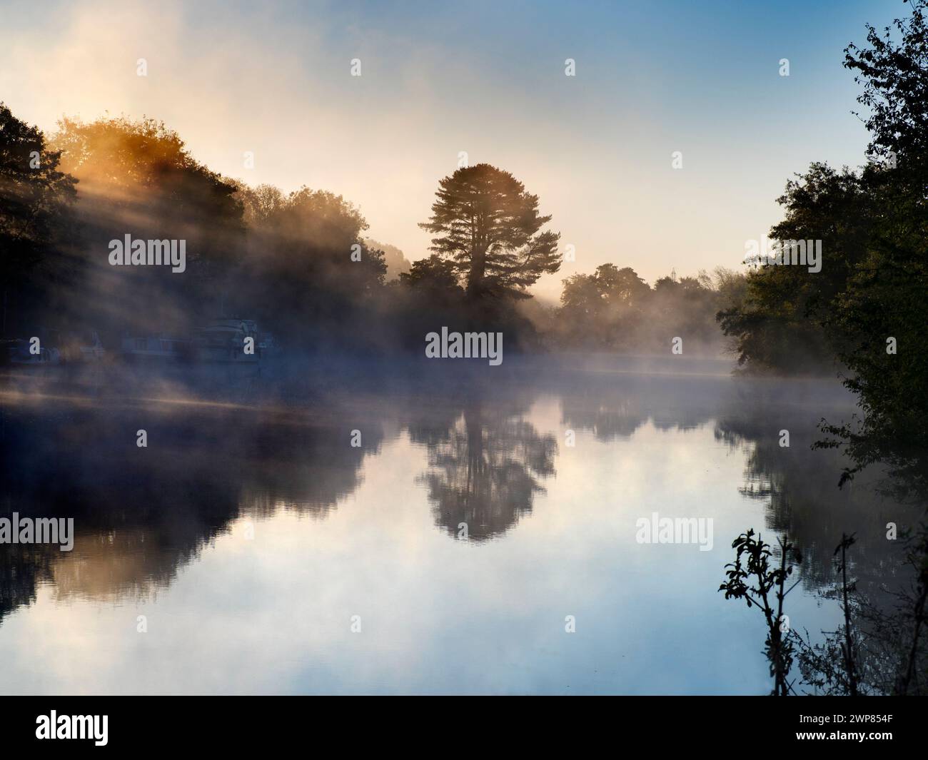 Here we see a line of pleasure boats moored by the Thames by Kennington, just outside Oxford. It's a misty Autumn sunrise. Seen from Thames Path - a w Stock Photo