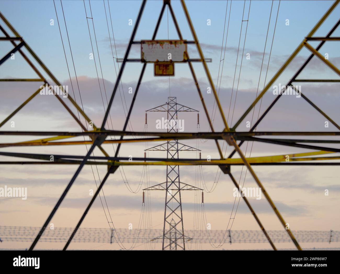 I love electricity pylons; I find their abstract, gaunt shapes endlessly fascinating. Here we see some lined up in a distant field in Lower Radley, si Stock Photo