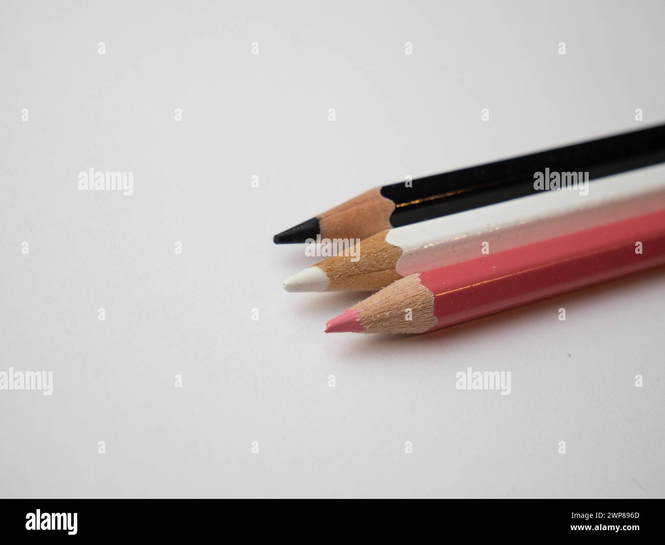 A close-up of assorted colorful pencils arranged on a white table surface Stock Photo