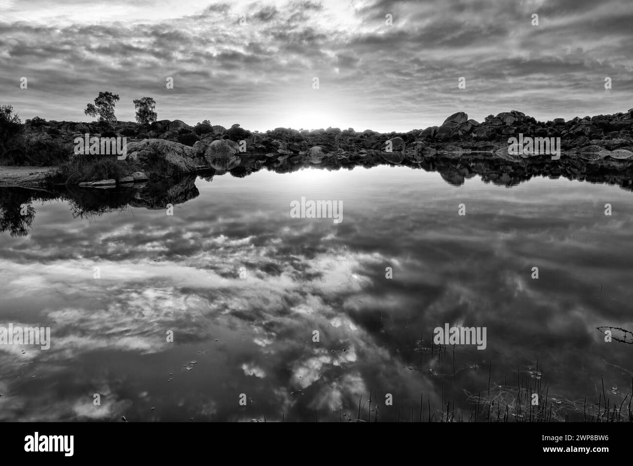 A grayscale shot of a sunny sky over a lake in Barruecos, Extremadura, Spain Stock Photo