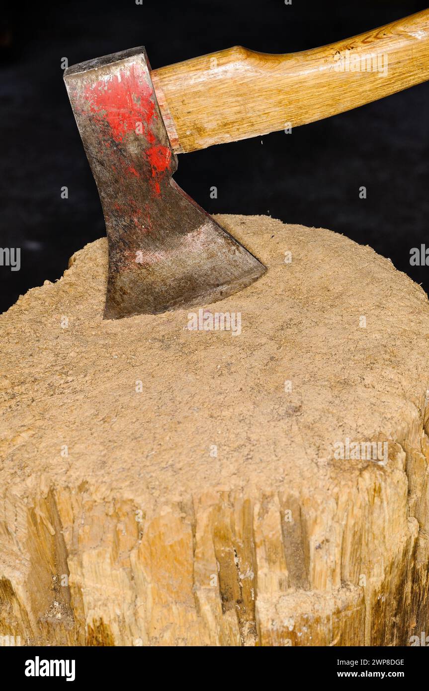 An Ax with wood handle is stuck in a wood Stock Photo