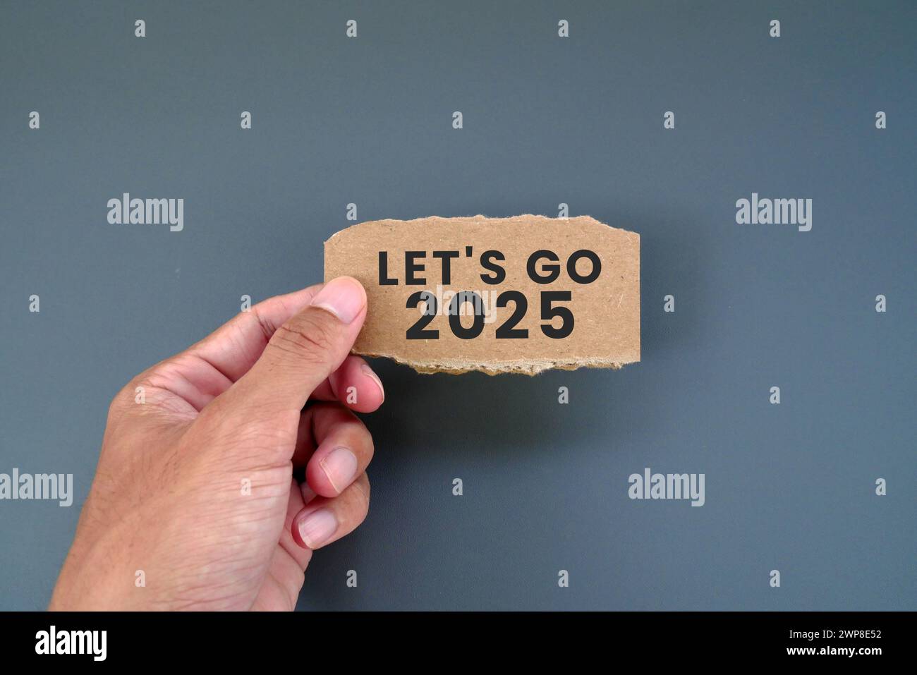 Man holding torn cardboard note with text LET'S GO 2025 Stock Photo Alamy