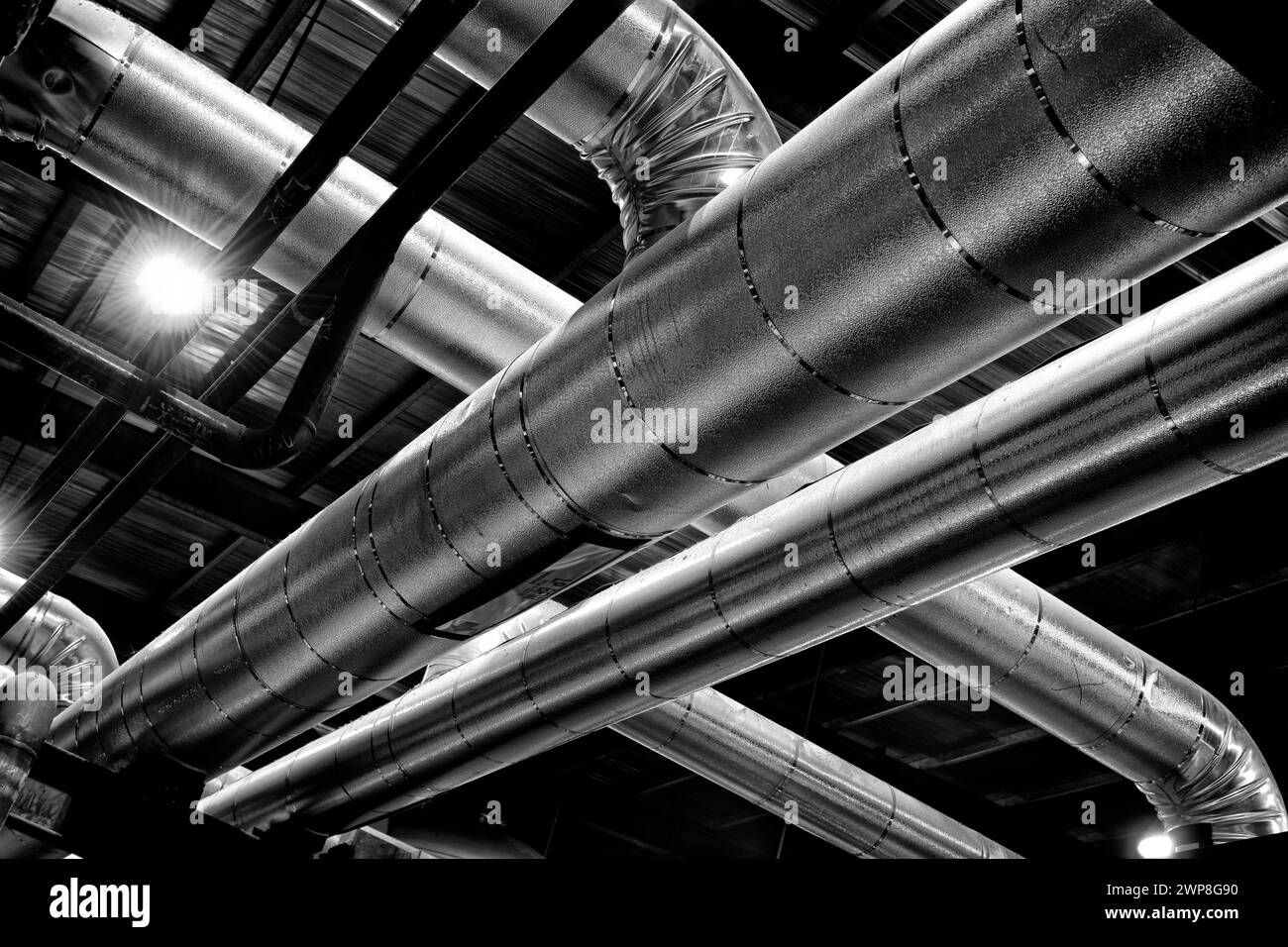 A black and white photograph of shiny pipes at an industrial oil refinery Stock Photo
