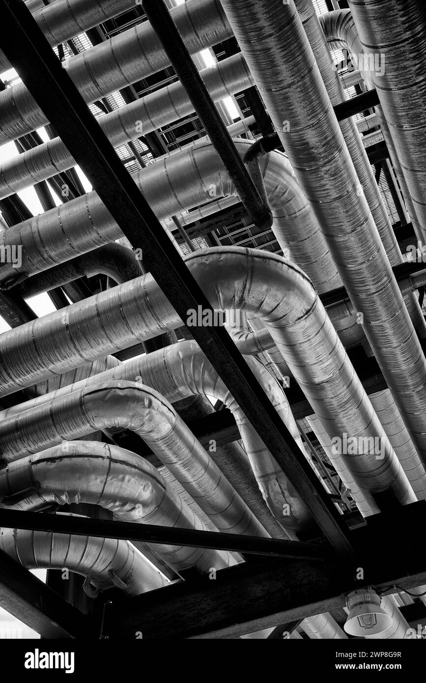 A black and white photograph of shiny pipes at an industrial oil refinery Stock Photo