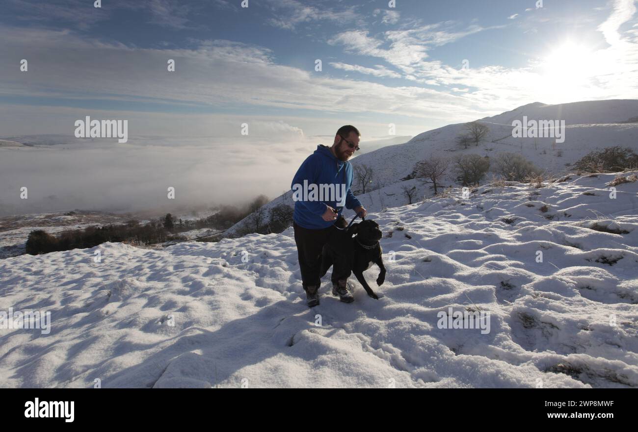16/01/13  After the coldest night of the winter, Chris Wycech walks his dog Oscar on Mam Tor overlooking a cloud inversion above Castleton, in The Pea Stock Photo