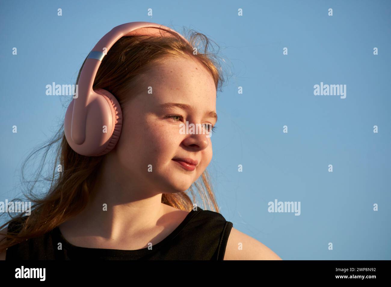 young 10 year old british irish girl wearing black dress and headphones during golden hour sunset Lanzarote, Canary Islands, spain Stock Photo