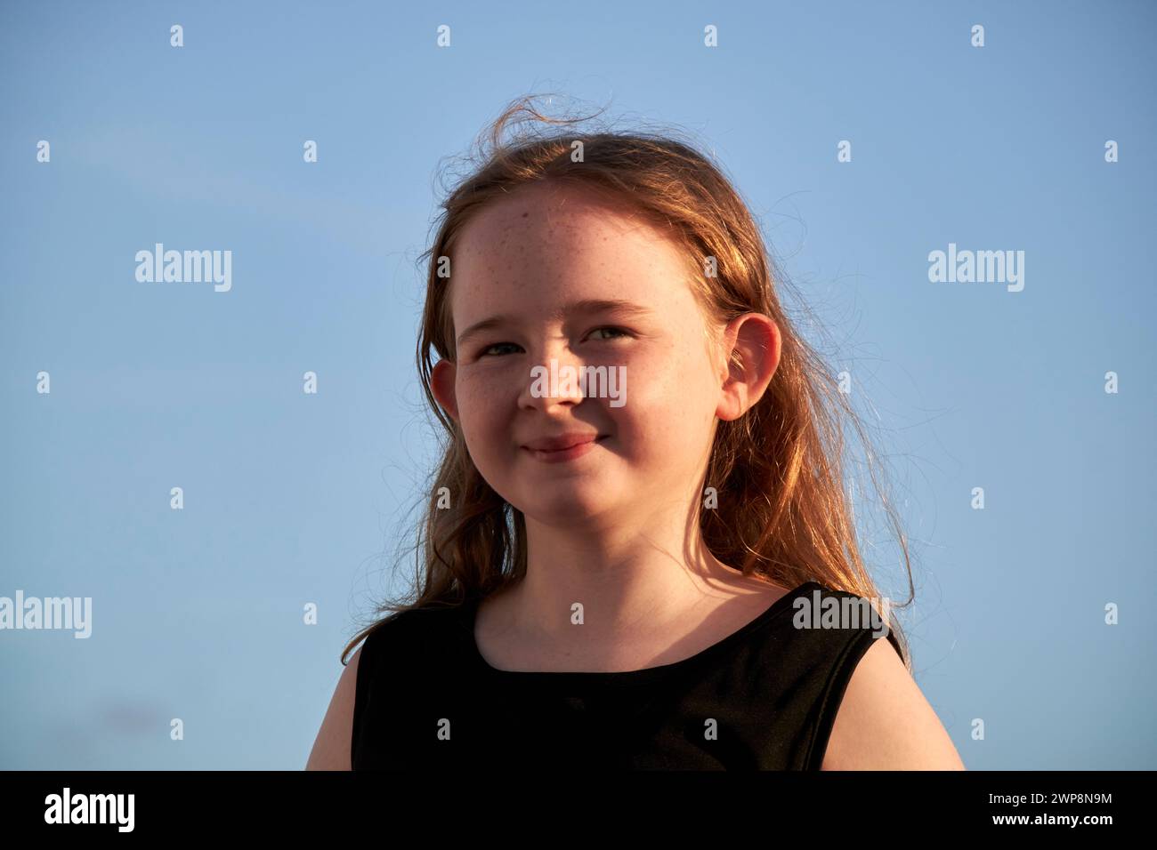 young 10 year old british irish girl wearing black dress smiling looking to camera during golden hour sunset Lanzarote, Canary Islands, spain Stock Photo