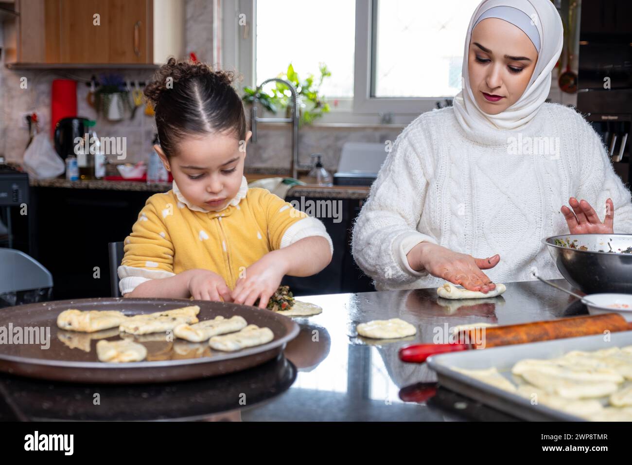 granddaughter helping her grandmother in making pastries  in kitchen , mother love emotions Stock Photo