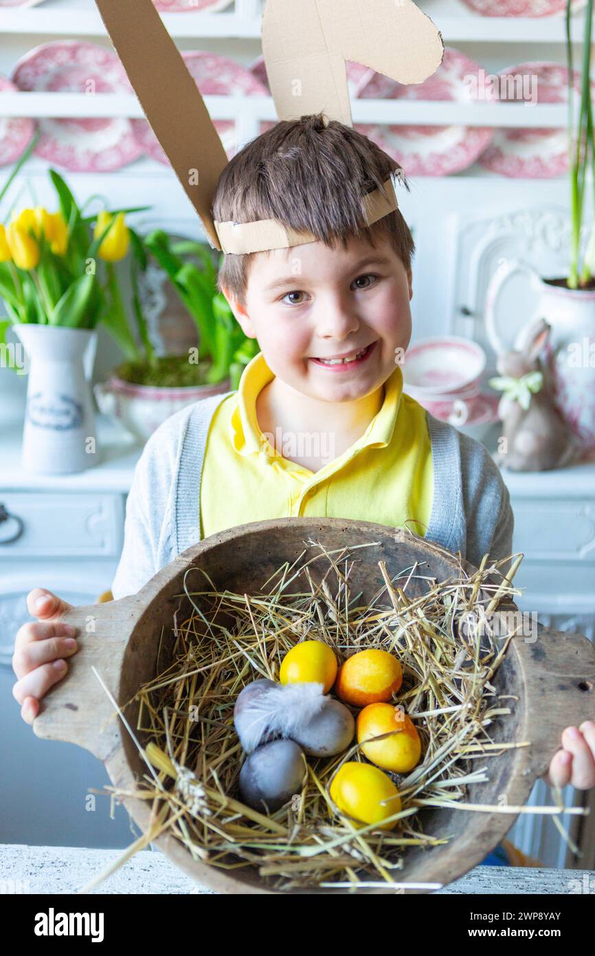3 March 2024: Little boy holds a rustic Easter nest with straw and ...