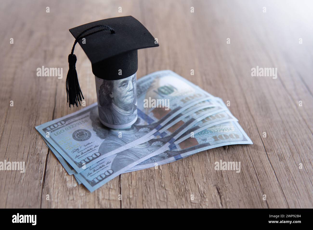 Closeup image of graduation cap and money on table. Scholarship, educational fees concept. Copy space for text. Stock Photo