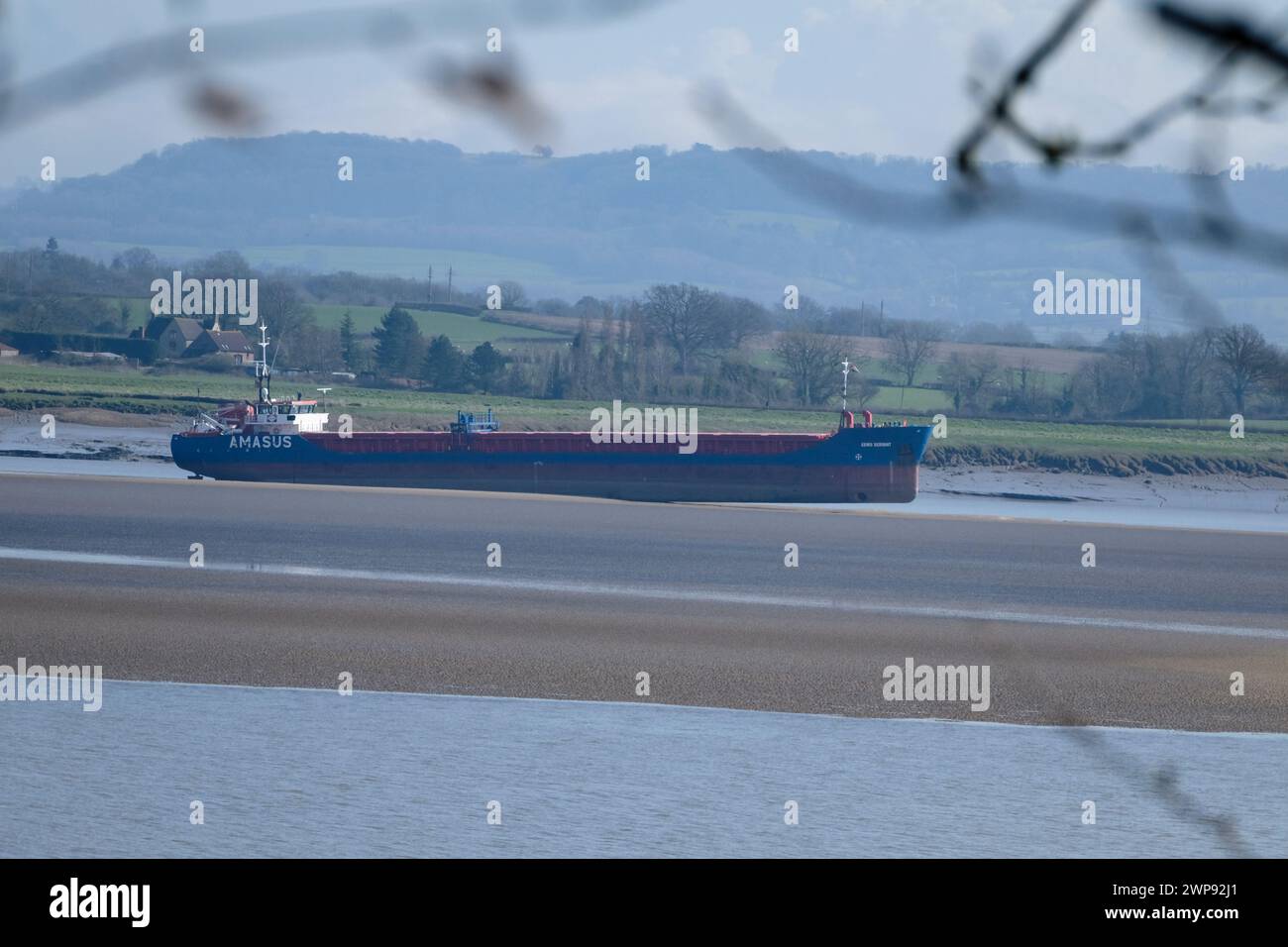 Sharpness, UK. 6th Mar, 2024. The cargo ship EEMS Servant has become stuck on a sandbank in the Severn Estuary near Sharpness docks. Stuck since Monday the ship is waiting for higher tides when an attempt will be made by local tugs to pull her off the sand bank. It is thought that recent heavy rain has moved the sands. The crew are safe onboard. Pictures taken from adjacent Lydney Harbour. Credit: JMF News/Alamy Live News Stock Photo