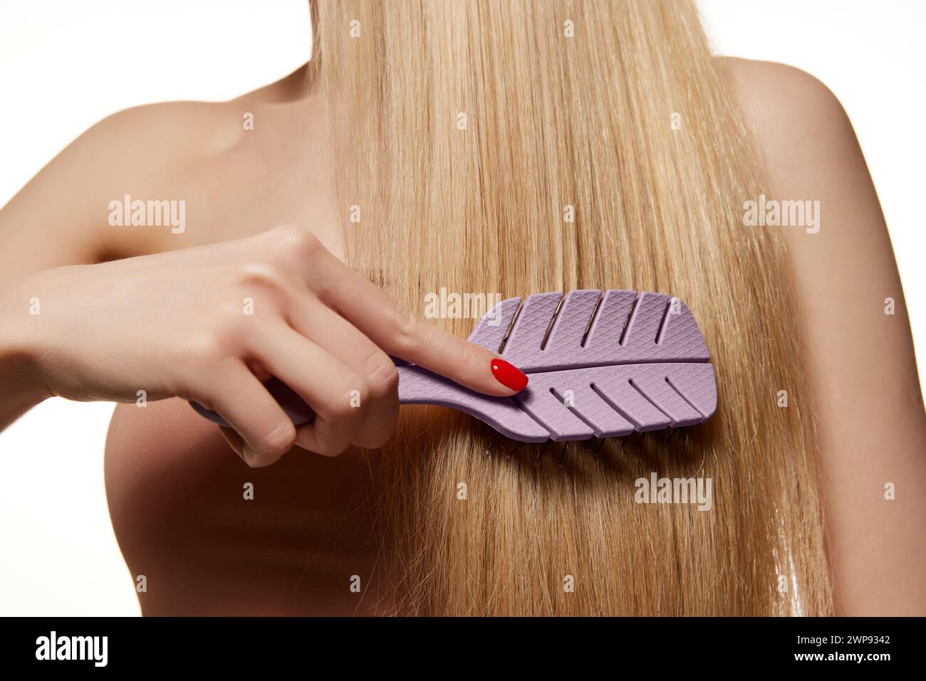 Cropped image of female straight blonde hair. Woman brushing hair, taking care isolated against white studio background Stock Photo