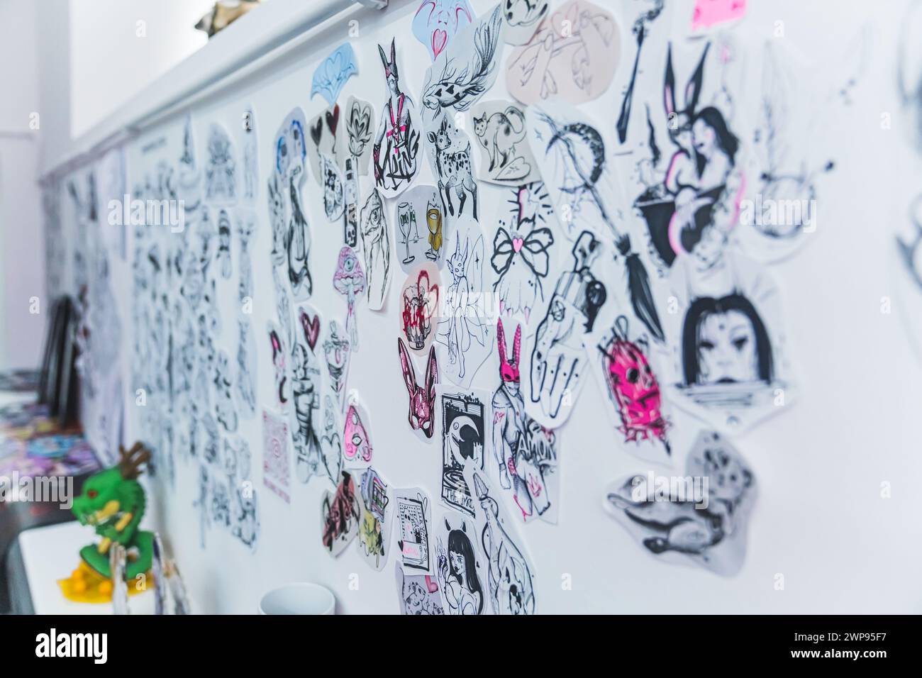 06.06.2023 Warsaw, Poland. Various sketches and designs made by professional tattoo artists and stick onto a white wall in a tattooing studio. Indoor shot. Art on paper. High quality photo Stock Photo