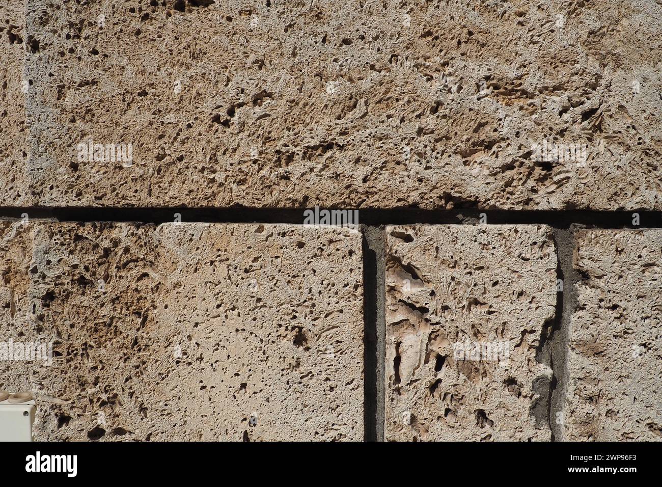 Textured wall lined with beige shell rock tiles. Close-up of a wall made of ancient shell rock. Holes, irregularities of natural building material Stock Photo