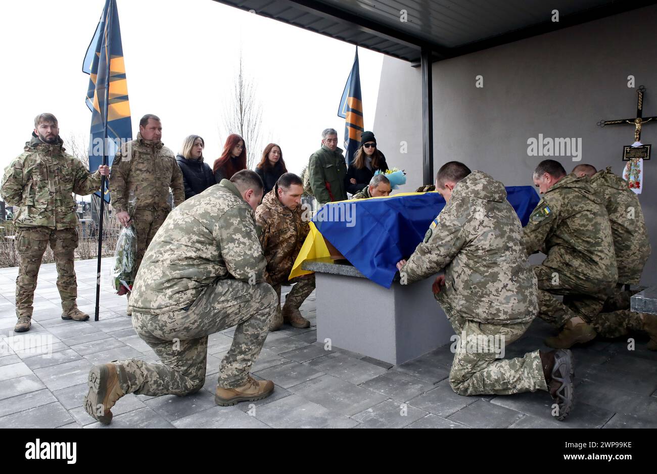 BUCHA, UKRAINE - MARCH 5, 2024 - Servicemen cover the coffin with a national flag during the memorial service for Ukrainian defender Daniil Semenenko who was killed in action against Russian invaders on the Donetsk axis on February 29, 2024, on the Alley of Heroes, Bucha, Kyiv region, northern Ukraine. Stock Photo
