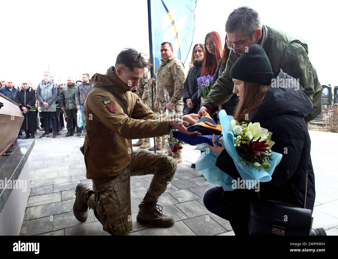 BUCHA, UKRAINE - MARCH 5, 2024 - Widow Alina Semenenko accepts the combat flag during the memorial service for Ukrainian defender Daniil Semenenko who was killed in action against Russian invaders on the Donetsk axis on February 29, 2024, on the Alley of Heroes, Bucha, Kyiv region, northern Ukraine. Stock Photo