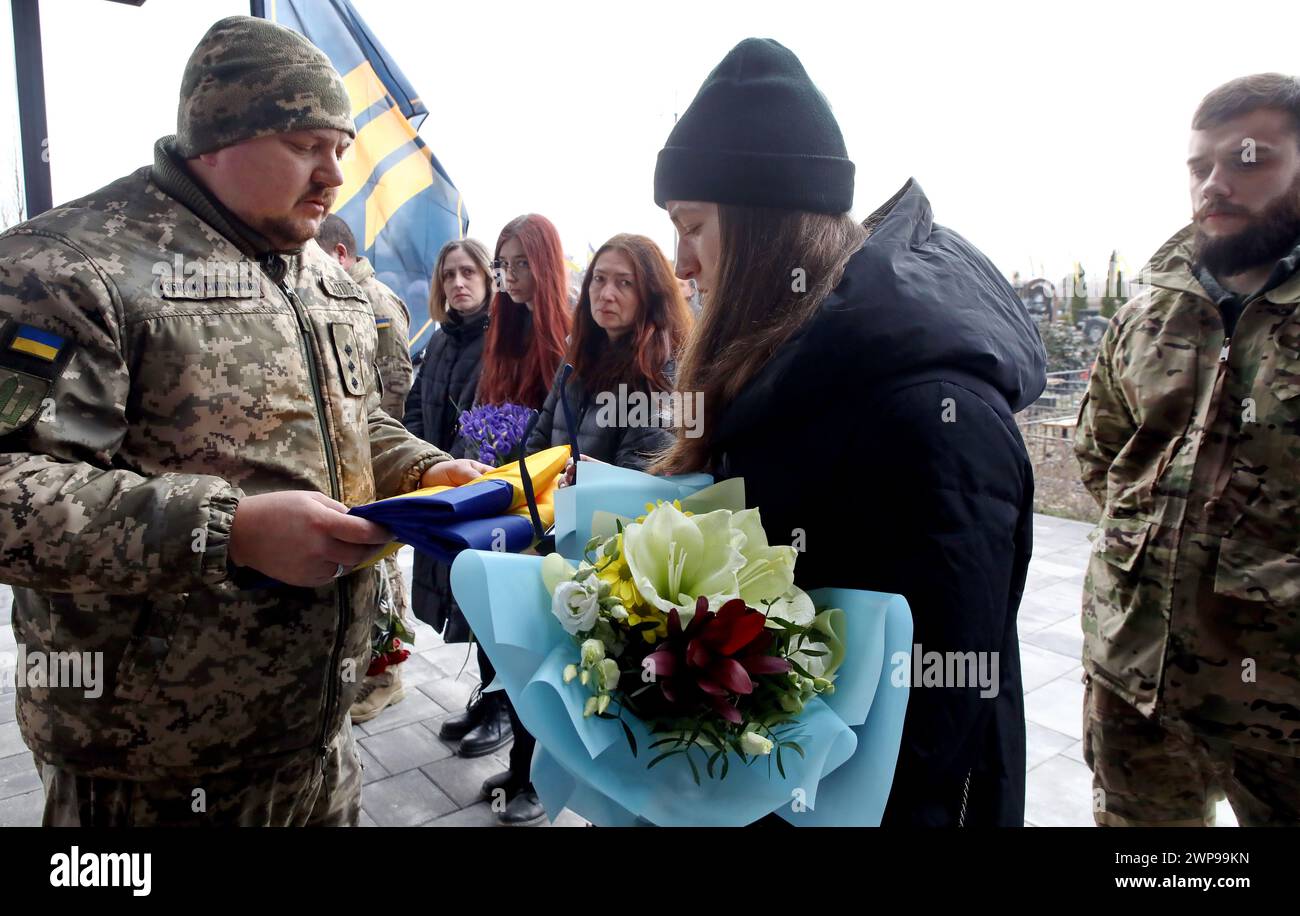 BUCHA, UKRAINE - MARCH 5, 2024 - Widow Alina Semenenko accepts the combat flag during the memorial service for Ukrainian defender Daniil Semenenko who was killed in action against Russian invaders on the Donetsk axis on February 29, 2024, on the Alley of Heroes, Bucha, Kyiv region, northern Ukraine. Stock Photo