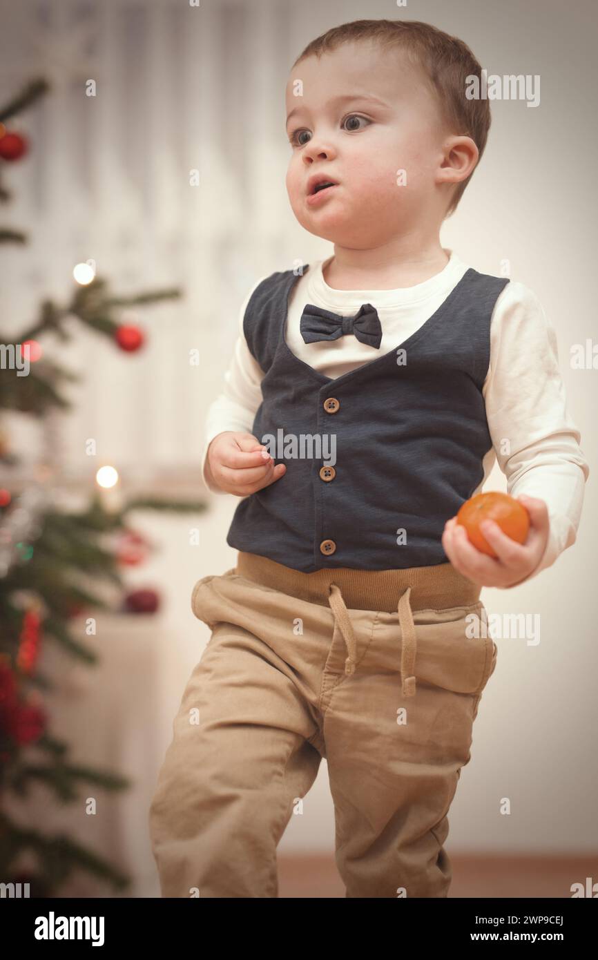 Little boy at time of christmas day unpacking gifts near tree Stock Photo