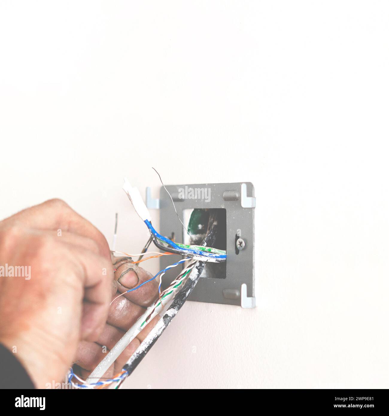 Electrician's hands when installing the socket and connecting the Internet Stock Photo