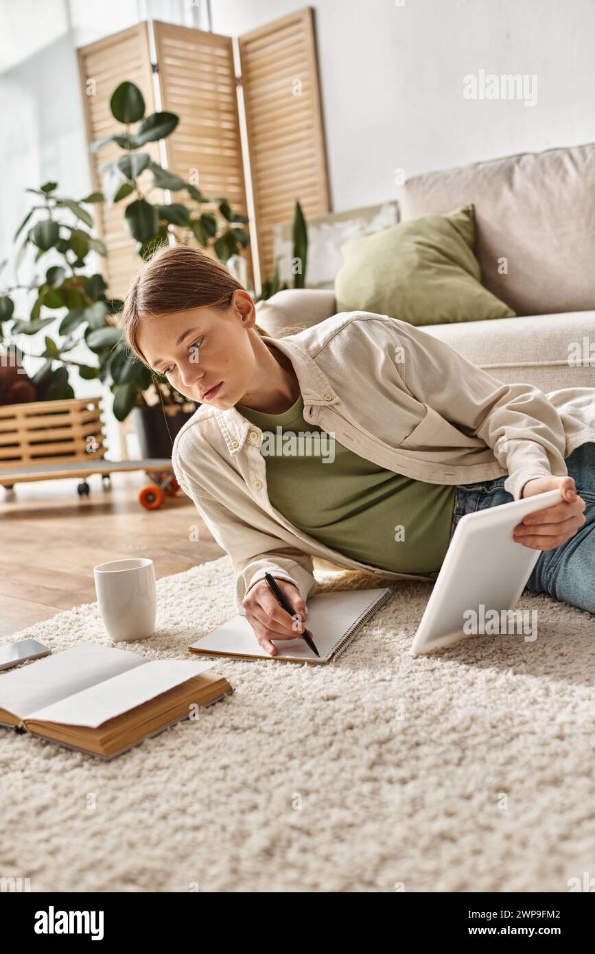 teenager girl holding tablet and taking notes while making her homework ...