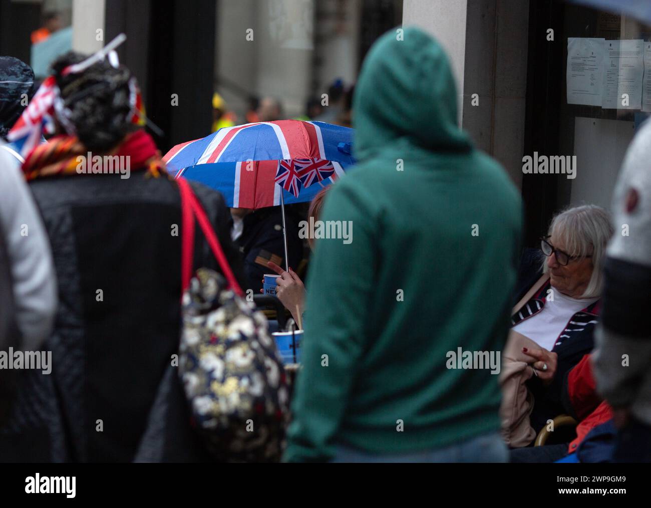 People gather to view the coronation of King Charles III in London. Stock Photo